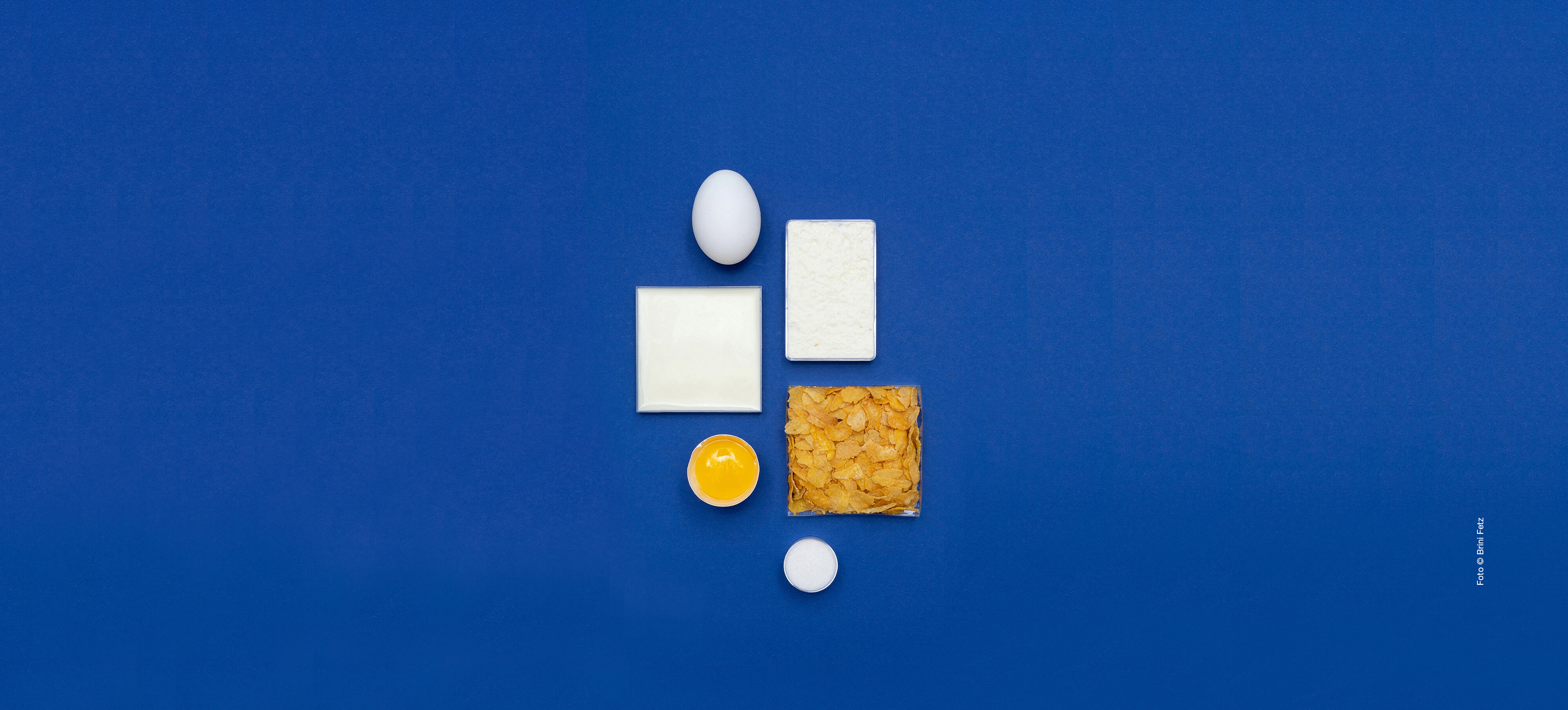 Dekoratives Bild, das angeordnete Lebensmittel zeigt wie Eier, Milch oder Cornflakes